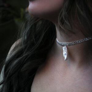 Close-up of a silver pendant necklace worn by a woman, showcasing fine jewelry and fashion.